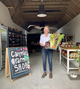 Trudi standing with veg box in shop
